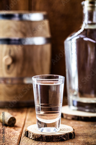 glass of distilled drink, strong alcoholic drink, detail image of pub, bar, with old oak barrel in the background