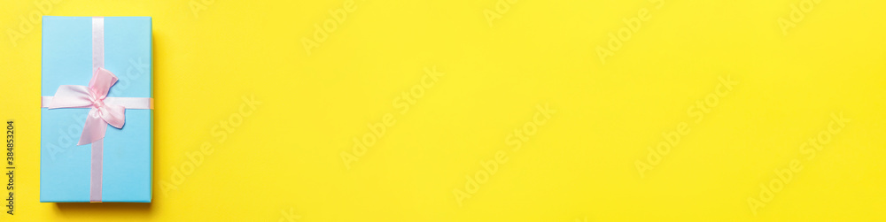 Christmas New Year birthday valentine celebration present romantic concept. Simply minimal design blue gift box isolated on yellow colorful background. Flat lay top view copy space, banner