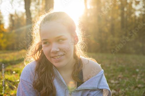 Young smiling woman in white hoodie sitting in the autumn park