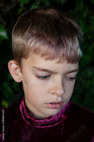 Close up portrait of boy with pink hair and purple clothes.