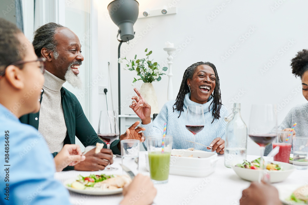 Family laughing over dinner at home Family laughing over dinner at home