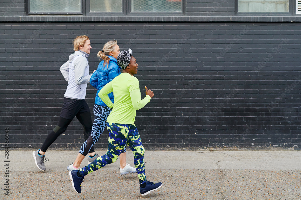 Smiling friends racing while out running Stock Photo | Adobe Stock