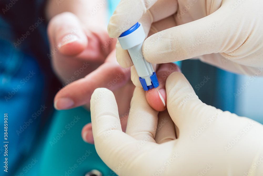 Nurse puncturing finger of patient to squeeze out blood sample for testing Nurse puncturing finger of patient to squeeze out blood sample for testing