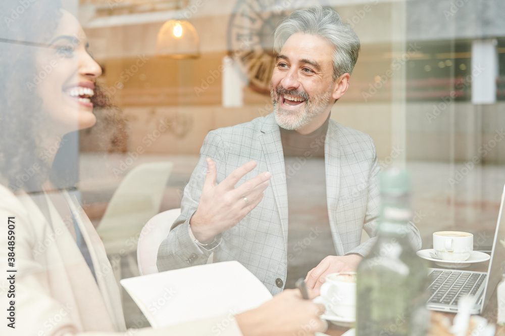Laughing work colleagues talking in a cafe Laughing work colleagues talking in a cafe
