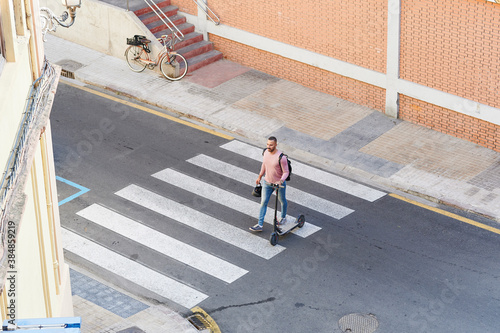 Man with a scooter crossing the street photo