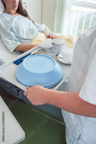 Nurse serving food in the hospital to a patient in bed © Kzenon