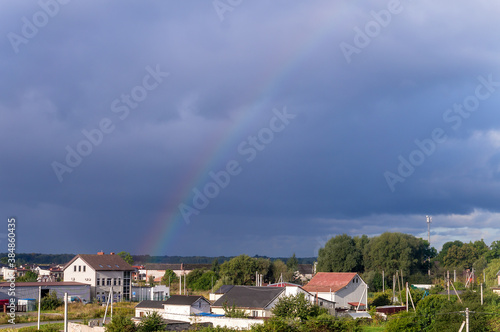 Rainbows in the sky. Rain clouds and rainbows. Rainbows over the roofs of houses. © SeagullNady