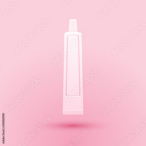 Paper cut Tube of toothpaste icon isolated on pink background. Paper art style. Vector.