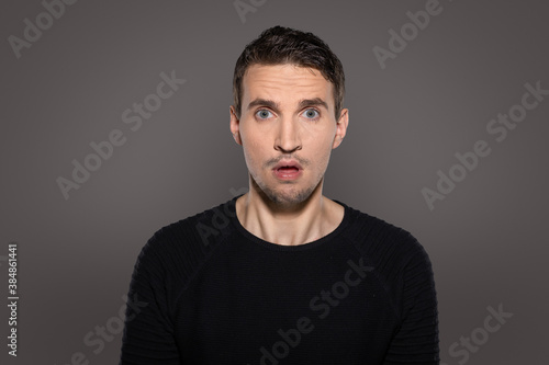 annoyed and shocked man look outraged with big eyes and open mouth straight into camera