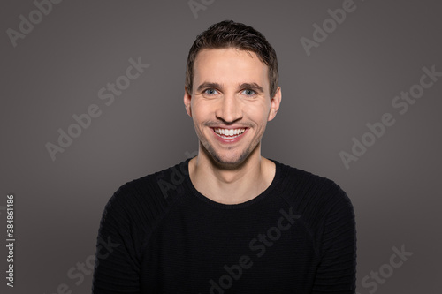 humorous happy man laughing intro camera with open mouth showing his teeth while reacting to funny situation