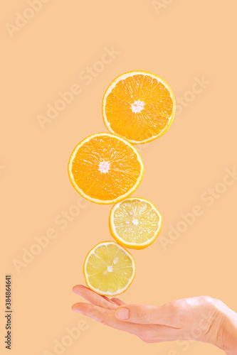 Cut in half lemons and oranges and a woman's hand on a pastel background. Surreal levitation effect. Citrus, vitamin C, fruit concept.