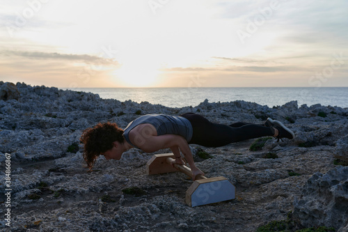 Woman using paralettes by the sea at dusk photo