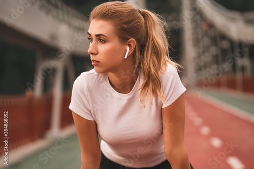 Beautiful sporty female jogger tired after running and looking away outdoors