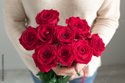 Woman holding fresh blossoming flower bouquet of red roses. Copy space