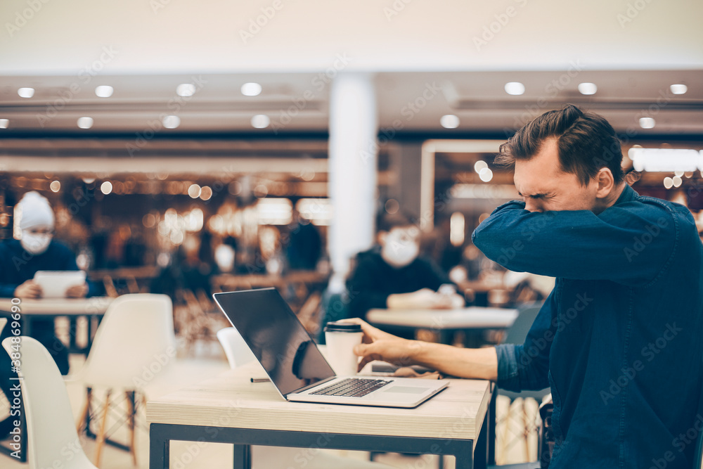 man sneezes sitting at a table in a cafe man sneezes sitting at a table in a cafe