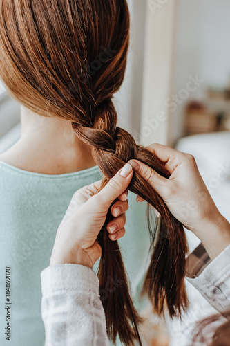Konstfotografi Two girls braid their hair at the window