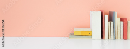 Books on a bookshelf and pink wall background. photo