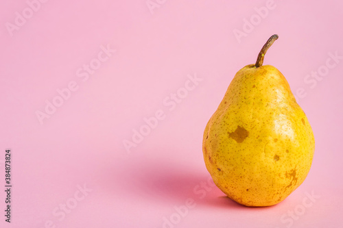 Fresh yellow ripe pear on pink background with abstract copy space