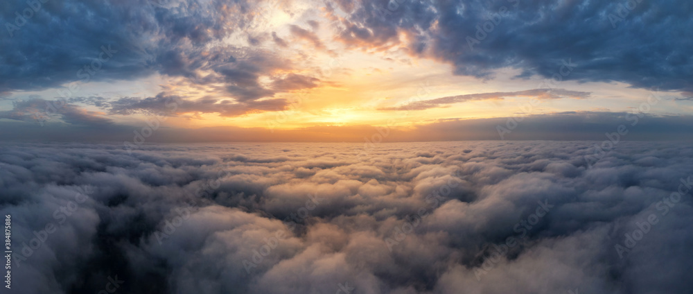 Beautiful dramatic sunset sky above fluffy clouds early in the morning. Drone view.