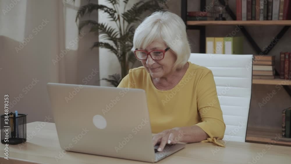 A senior concentrated business lady staring at the screen and lowered her eyeglasses while using laptop A senior concentrated business lady staring at the screen and lowered her eyeglasses while using laptop