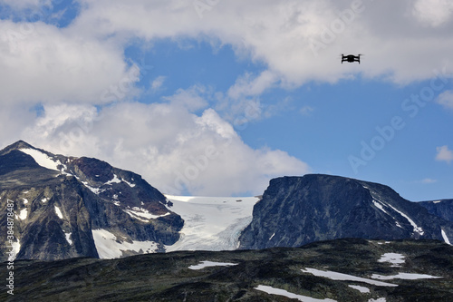 A drone is monitoring the glacier  between the dark mountains in Norway photo