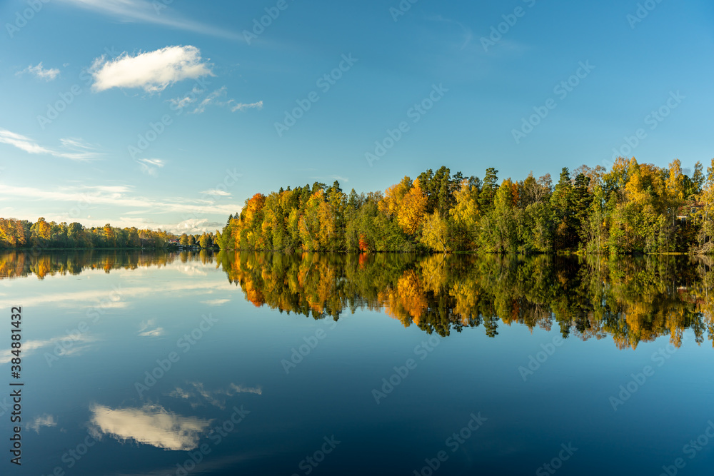 Beautiful autumn view across the Dal River in Sweden, with vibrant autumn colored trees mirroring in the dead calm water Beautiful autumn view across the Dal River in Sweden, with vibrant autumn colored trees mirroring in the dead calm water