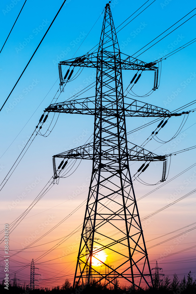 Fototapeta premium Electric power transmission lines. High voltage post. Industrial landscape. Electricity pylon at sunset sky on the background. Electric distribution station