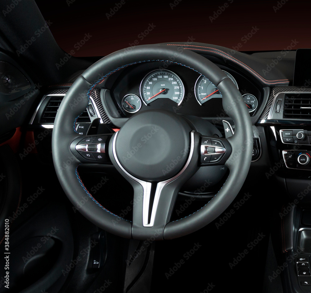 Modern luxury car Interior - steering wheel, shift lever and dashboard. Car interior luxury.Steering wheel, dashboard, speedometer, display. Red and black perforated leather cockpit