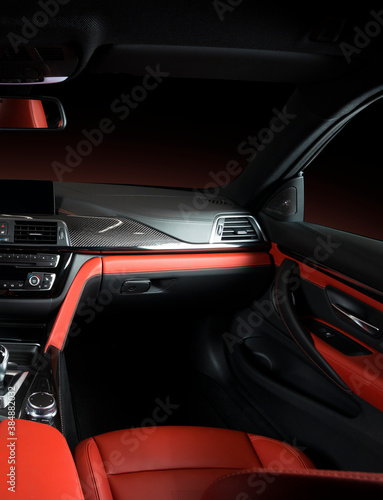Modern luxury car Interior - steering wheel, shift lever and dashboard. Car interior luxury.Steering wheel, dashboard, speedometer, display. Red and black perforated leather cockpit