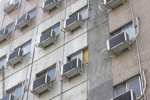 集合住宅の外壁に設置されたたくさんのエアコン室外機 © Paylessimages