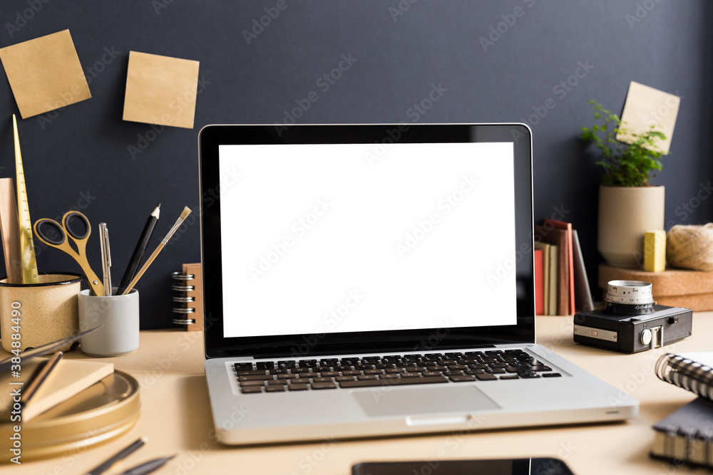 Fototapeta premium Table with laptop on a dark blue background. Artistic workspace. Mock up. 