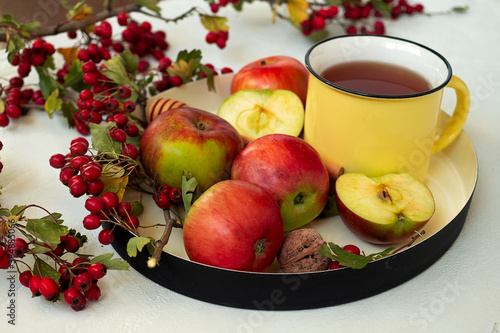 Cozy autumn hot spiced tea with honey, apples and red hawthorn berries on a tray. Still life on white background