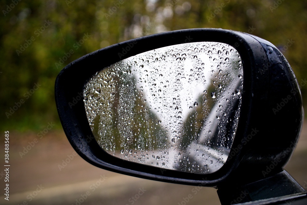 sideview, rearview mirror of a car on road with drops of rain at autumn rainy day ' sideview, rearview mirror of a car on road with drops of rain at autumn rainy day '