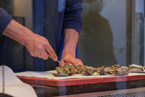 Selective focus at hand prepare fresh oysters on the countertop of seafood stall in market.