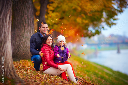 happy family playing among fallen leaves in autumn park