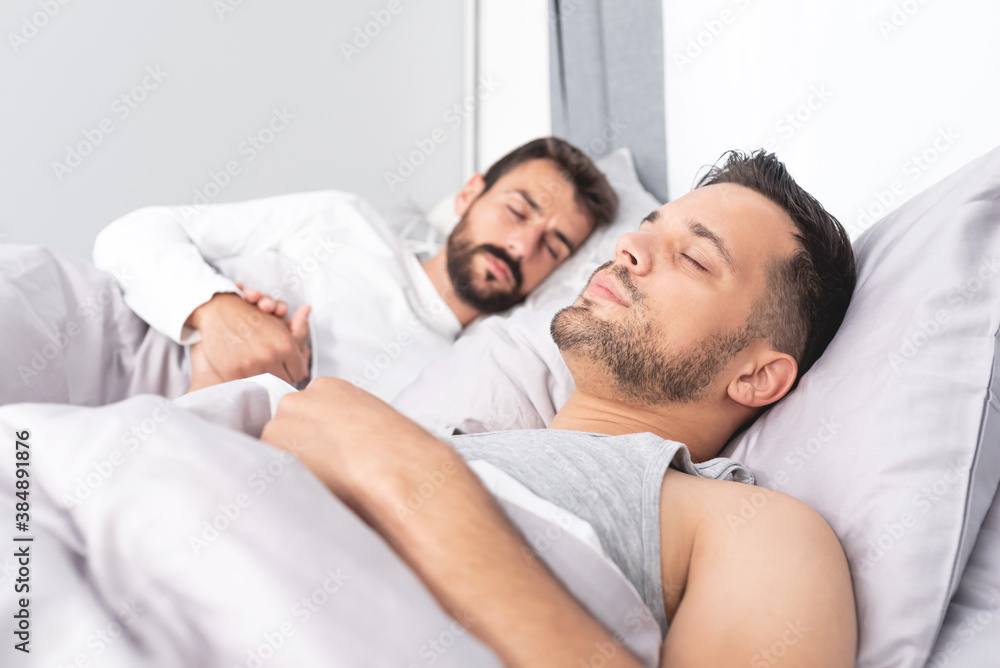Gay couple sleeping on bed at home