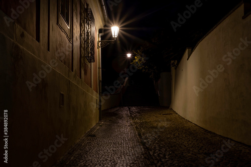 street lamp and sidewalk with cobblestones and light reflections after the rain in the center of the old town of Prague in the Czech Republic