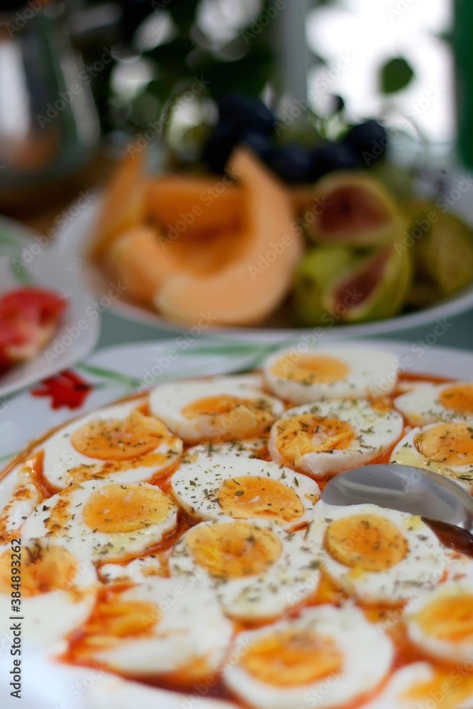 Boiled eggs with yoghurt sauce, tomato salda and various fruit on the breakfast table. Selective focus. Boiled eggs with yoghurt sauce, tomato salda and various fruit on the breakfast table. Selective focus.