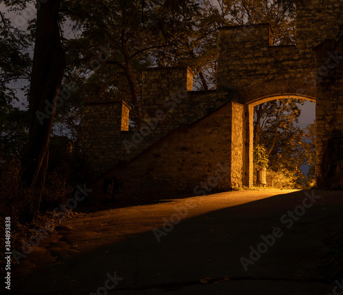 light from street lighting through the gate of the old wall from the 17th century in the center of Prague and a waste basket in a park in the Czech Republic at night