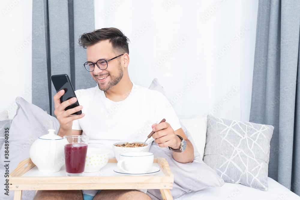 Man using mobile phone during morning breakfast in bed Man using mobile phone during morning breakfast in bed