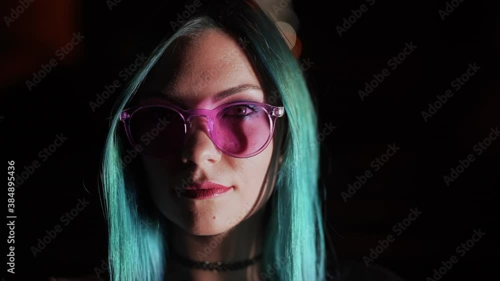 Portrait of millennial enigmatic pretty girl with unusual dyed blue hairstyle at night. Mysterious hipster woman in glasses. Portrait of millennial enigmatic pretty girl with unusual dyed blue hairstyle at night. Mysterious hipster woman in glasses.