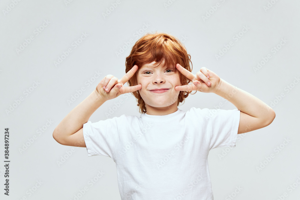 Cheerful red-haired boy holds his hands near his face close-up cropped view Cheerful red-haired boy holds his hands near his face close-up cropped view