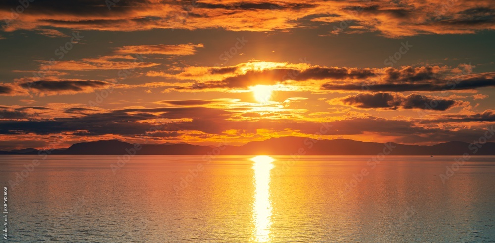 Fototapeta premium Sunset over the ocean water with the Alaskan Coast in silhouette