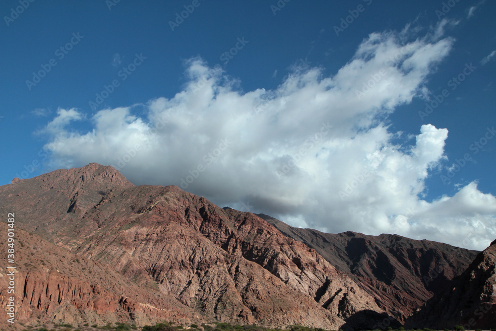 Andes mountain range.View of the brown rocky mountain under a blue sky with clouds. 