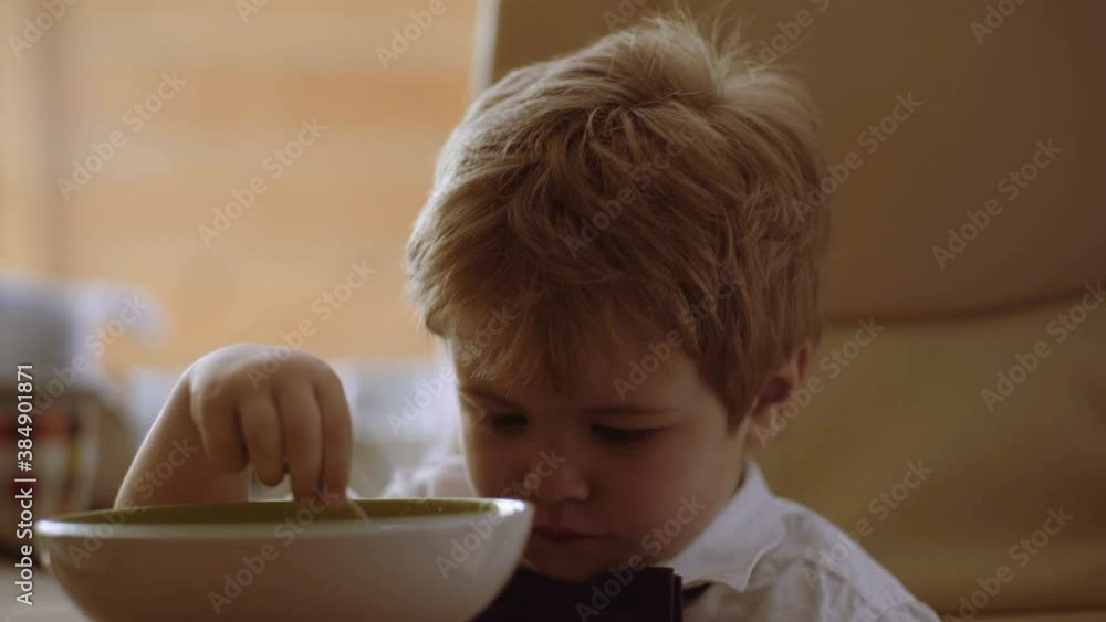 Little kid enjoying his porridge. Funny boy eat porridge with milk. Boy watch cartoons Little kid enjoying his porridge. Funny boy eat porridge with milk. Boy watch cartoons