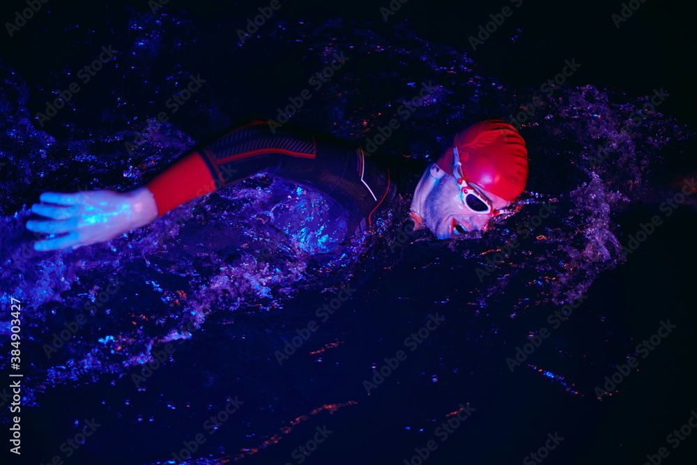 real triathlon athlete swimming in dark night real triathlon athlete swimming in dark night