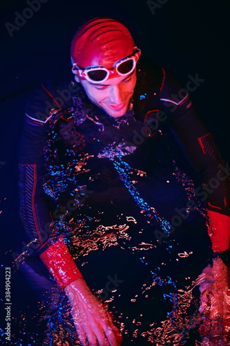 authentic triathlete swimmer having a break during hard training on night neon gel light © .shock