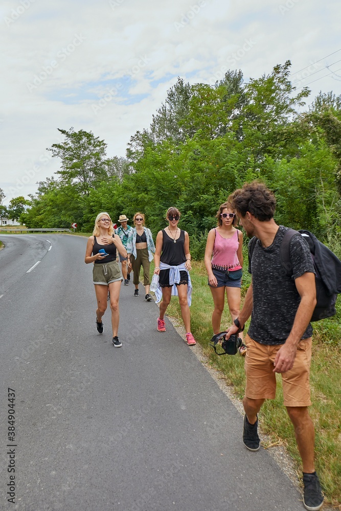 Obraz premium Young people walking by the roadside going on a summer vacation trip