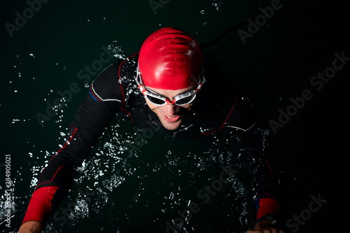 triathlon athlete swimming in dark night wearing wetsuit photo