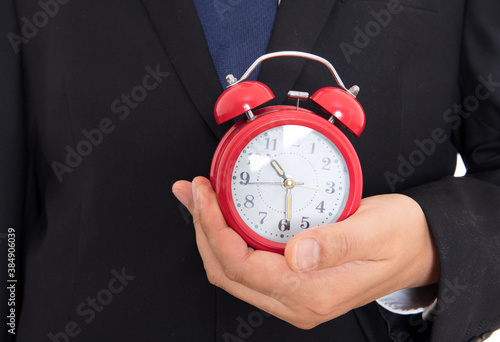 Man in black suit holding alarm clock in hand